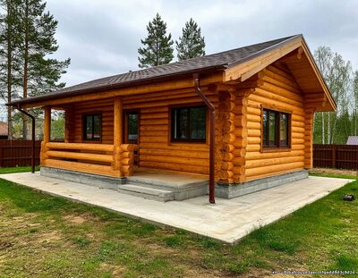 низкая бетонная отмостка вокруг дома из бревна на ленточном фундаменте